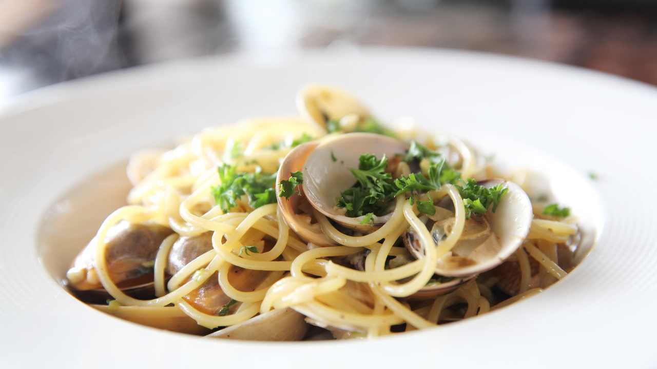 Spaghetti alle vongole su piatto di coccio bianco 