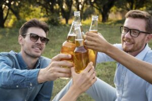 Ragazzi brindano con bottiglie di birra in un prato