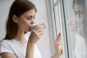 Ragazza alla finestra beve da tazza