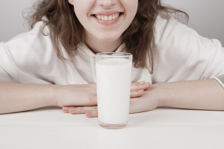 Ragazza che sorride davanti a un bicchiere di latte